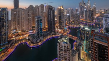 Dubai Marina ve JBR hava sahasındaki en yüksek bloktaki çeşitli gökdelenlerin görüntüsü suni kanalla gündüz gece geçiş zamanı. Gün batımından sonra birçok kule ve yat