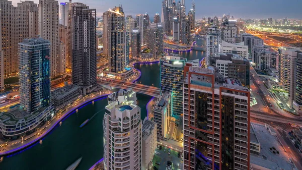 View of various skyscrapers in tallest recidential block in Dubai Marina aerial day to night transition timelapse with artificial canal and bridges over it. Many towers and yachts after sunset