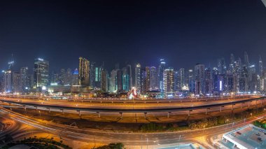 Dubai Marina Gökdelenleri ve Şeyh Zayed Yolu 'nun panorama' sı. Metro demiryolu gece uçuşları. Modern kulelerin yakınındaki bir otoyolda trafik var, Birleşik Arap Emirlikleri