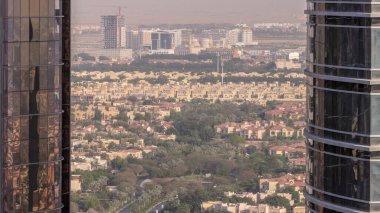 JLT semti gökdelenleri ve park zamanı olan yol trafiği arasındaki konut geliştirme alanının havadan görüntüsü. Arkasında inşaat alanı olan Dubai manzarası