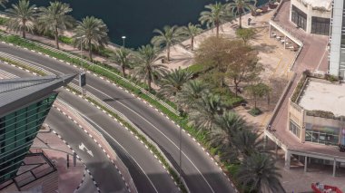 Dubai çok amaçlı emtia merkezi karma kullanım bölgesinin bir parçası olan JLT bölgesi hava zaman diliminde kavisli bir yolda trafik var. Palmiyeler göletin kıyısında