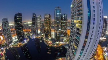 Dubai çok amaçlı emtia merkezi karma kullanım bölgesinin bir parçası olan JLT bölge hava sahasındaki panorama binalarından gece geçiş zamanına kadar. Göl kenarındaki gökdelenler
