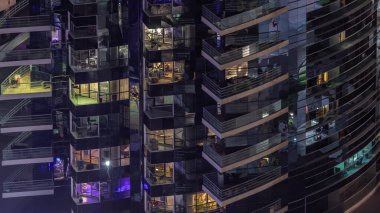 Apartman kulesindeki parlayan pencerelerin gece görüşü. Odalarında ışıklar olan yüksek gökdelenli