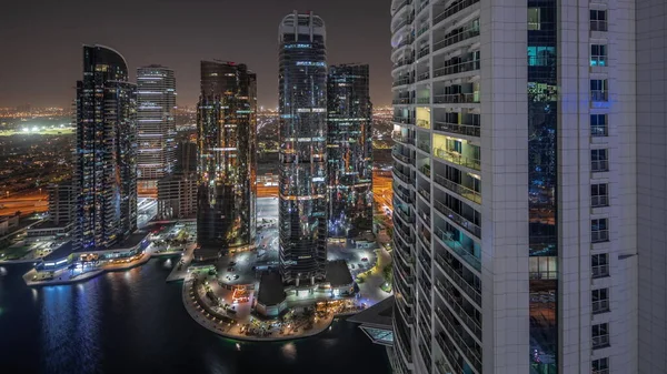 Panorama showing tall residential buildings at JLT district aerial night timelapse, part of the Dubai multi commodities centre mixed-use district. Illuminated towers and skyscrapers