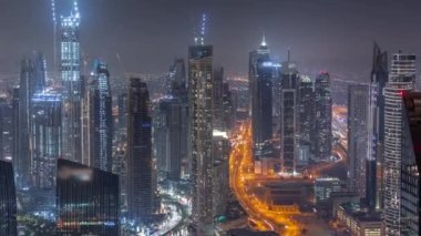 Şehir merkezinin ufuk çizgisi, modern mimari biçimle gece zamanının üstünde. Dubai iş sahasının havadan panoramik görüntüsü aydınlatma kuleleri.