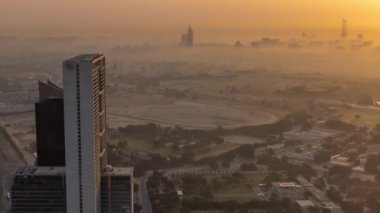 Dubai, BAE 'de güneş doğarken arka planda gökdelenleri olan Zabeel bölgesindeki villalar. Evleri ve yolları sabah sisiyle kaplı caddelerde trafik vardı.