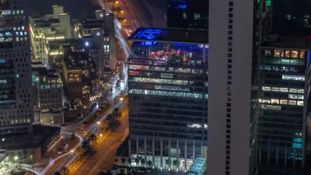 オフィスビルは夜間のタイムラプスの間 金融街の空中に照明が設置されている ホテルへのトップビューとライトがオフになって上から道路上のトラフィック — ストック動画