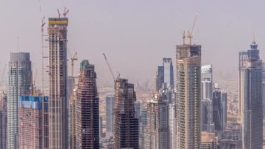 Dubai şehir merkezinde büyük ölçekli bir konut kompleksi inşaatı var. İnşaat vinçleri hava zaman ayarlı. Gün boyunca gölgeler hızla hareket ederken,