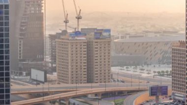 Büyük otoyol kavşağı ve Dubai su kanalı. Arka planda yaya köprüsü var. Gün batımında vinçler havada uçuşuyor. Birçok ev ve villa kavşağın arkasında..
