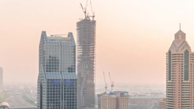 Dubai şehrinin ufuk çizgisi panoramik manzaralı metro ve arabaların hareket halindeki şehirleri en işlek otoban zaman çizelgesi. Gün batımında gökdelenlerle çevrili bir kavşak.