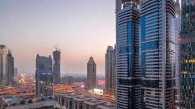 Günbatımından sonra Dubai Uluslararası Finans Bölgesi 'nin hava görüntüsü ve birçok gökdelen gece gündüz geçiş zamanı. Otoparkın yanındaki kavşakta trafik vardı. Dubai, BAE.