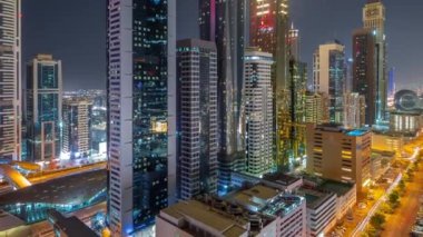 Dubai Uluslararası Finans Bölgesi 'nin birçok gökdelenli gece görüşü. Çok katlı otopark ve metro istasyonunun yakınındaki bir yolda trafik vardı. Dubai, BAE.
