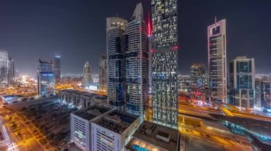 Dubai Uluslararası Finans Bölgesi 'nin panoramik hava manzarası ve birçok gökdelen gece zaman çizelgesi. Çok katlı otoparkın yakınındaki yoğun otoyoldaki kavşakta trafik vardı. Dubai, BAE.