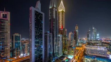 Dubai Uluslararası Finans Bölgesi 'nin panoramik hava manzarası ve birçok gökdelen gece zaman çizelgesi. Meşhur kulelerin yakınındaki yolda trafik vardı. Dubai, BAE.