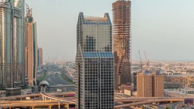 Dubai şehrinin ufuk çizgisi panoramik manzaralı metro ve araçlar şehrin en işlek otoban sabah saatlerinde hareket ediyor. Gün doğmadan önce uzun gölgelerle çevrili bir kavşak.