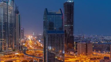 Dubai şehrinin ufuk çizgisi panoramik manzarası metro ve arabalar şehirlerde en yoğun karayolu üzerinde gece gündüz geçiş zamanı. Gün doğmadan önce gökdelenlerle çevrili bir kavşak.