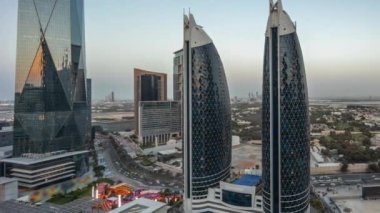 Günbatımından sonra Dubai Uluslararası Finansal Bölgesi 'nin havadan görünüşü ve birçok gökdelenin gece gündüz geçiş panoramik zamanlaması. Çatıda yürüme alanı olan alışveriş caddesi yakınındaki yollarda trafik vardı.