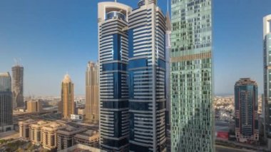 Dubai Uluslararası Finans Bölgesi 'nin panoraması. Gün doğumundan günbatımına kadar birçok gökdelen zaman çizelgesi var. Bütün gün boyunca çok katlı otoparkın yakınındaki bir yolda trafik vardı. Dubai, BAE.