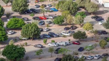 Otoparkta park halindeki sıra sıra yeşil yapraklı ağaçların arasına park edilmiş araçlar tüm gün boyunca yukarıdan izleniyor ve gölgeler hızla hareket ediyor. Dubai 'deki yerleşim bölgesinin havadan görüntüsü