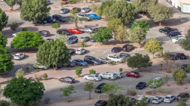 그림자가 속도로 이동하면서 위에서 바라볼 수있는 잎나무들 사이에 주차장에 자동차들이 — 비디오