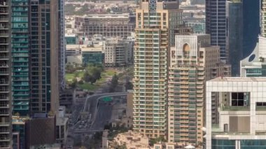 Dubai Marina ve Medya Şehri bölgelerinde modern gökdelenler ve ofis binaları havadan zaman ayarlı. Yeşil park yakınlarındaki üst geçitte trafik ve kavşak.