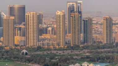 Dubai 'de avuçlarında golf sopası olan lüks meskenler. Gün batımında Yeşiller ve Barsha bölgesindeki kulelerin hava görüntüsü