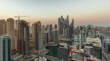 Dubai Marina hava sahasının en uzun bloğundaki çeşitli gökdelenlerin panoramasından gece gündüz yapay kanalla geçiş zamanına kadar. Günbatımından sonra JBR bölgesinde birçok kule ve yat var.