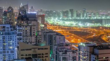 Dubai 'de lüks bir semt ve golf kulübü gece saatleri var. Dubai marina gökdelenleri yakınlarındaki kulelerin ve yol kavşağının havadan görüntüsü