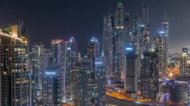 Dubai Marina hava sahasının en uzun bloğundaki çeşitli gökdelenlerin görüntüsü suni kanallı gece zaman ayarlı. Parlayan pencereleri ve yatları olan pek çok kule