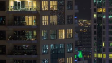 Parlak panoramik pencereli dış apartman binasının gece görüşü. Işıklı gökdelenle aydınlatılmış yüksek bir gökdelen