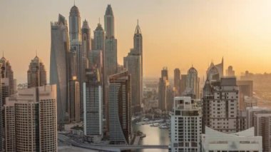 Sunrise Airial Timelapse sırasında Dubai Marina 'nın en yüksek karşılama bloğundaki yapay kanallı çeşitli gökdelenlerin görüntüsü. Turuncu gökyüzü ile sabahın erken saatlerinde pek çok kule ve yat