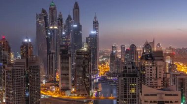 Dubai Marina hava sahasının en yüksek bloğundaki çeşitli gökdelenlerin görüntüsü. Gece gündüz yapay kanalla geçiş zamanı. Güneş doğmadan önce çok sayıda kule ve yat