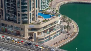 Dubai Marina rıhtımı ve yüzme havuzu zaman ayarlı şehir turu. Kanallar boyunca gökdelenlerin havadan görüntüsü. İnşaat işçileri fayans yolu yapıyor.