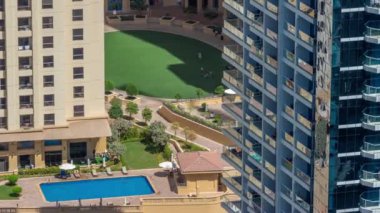 Çatıdaki yüzme havuzu, JBR bölgesinin havuz manzarası. İnsanlar yeşil bir çimenlikte yüzüyor ve dinleniyorlar. Dubai, BAE