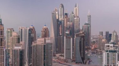 Dubai Marina hava sahasının en uzun bloğundaki çeşitli gökdelenlerin görüntüsü suni kanallı panoramik zaman geçişi. Gün batımından sonra birçok kule ve yat