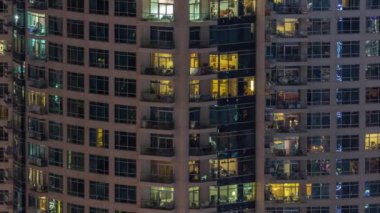 Dışarıdaki apartmanın akşam manzarası. Parlayan pencereleri olan bir bina. Işıklı gökdelenle aydınlatılmış yüksek bir gökdelen