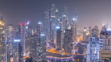 Dubai Marina hava sahasının en yüksek bloğundaki çeşitli gökdelenlerin görüntüsü tüm gece boyunca yapay kanallı. Yanıp sönen ışıkları ve yatları olan bir sürü kule. Bulutlu gökyüzü