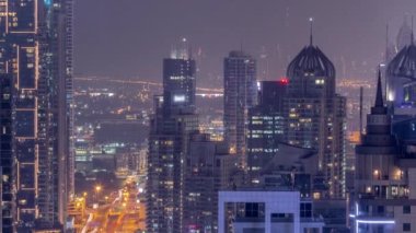 Dubai Marina ve Media City semtleri modern gökdelenler ve ofis binaları tüm gece boyunca antenli. Üstgeçitte trafik ve ışıkların kapandığı kavşak.