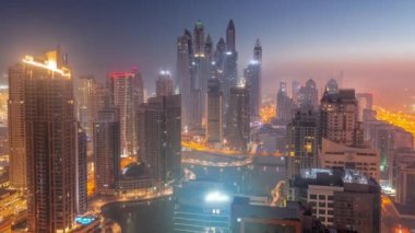 Dubai Marina hava sahasının en yüksek bloğundaki çeşitli gökdelenlerin görüntüsü. Gece gündüz yapay kanalla geçiş zamanı. Güneş doğmadan önce birçok kule ve yat sisli.