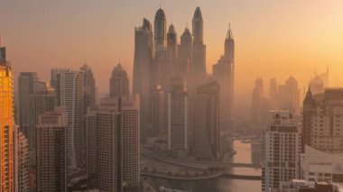 Sunrise Airial Timelapse sırasında Dubai Marina 'nın en yüksek karşılama bloğundaki yapay kanallı çeşitli gökdelenlerin görüntüsü. Birçok kule ve yat sisli sabahın erken saatlerinde