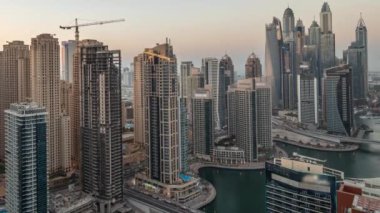 Dubai Marina ve JBR hava sahasındaki en yüksek bloktaki çeşitli gökdelenlerin görüntüsü suni kanalla gündüz gece geçiş zamanı. Gün batımından sonra birçok kule ve yat