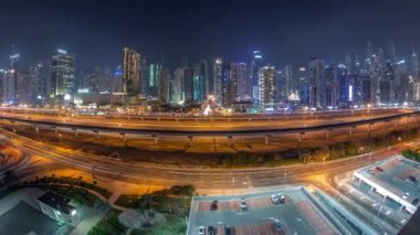 Dubai Marina Gökdelenleri ve Şeyh Zayed Yolu 'nun panorama' sı. Metro demiryolu gece uçuşları. Modern kulelerin yakınındaki bir otoyolda trafik var, Birleşik Arap Emirlikleri