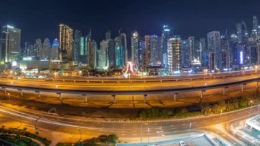 Tüm gece boyunca Dubai Marina gökdelenleri ve Şeyh Zayed yolu metro antenli panorama. Modern kulelerin yakınındaki bir otoyolda trafik var, Birleşik Arap Emirlikleri