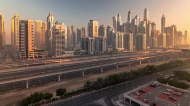 Dubai marinası güneş doğarken sabah saatlerinde gökdelenlerin en yüksek binası. JLT bölgesinden apartman binalarına, otellere ve otoyola yakın ofis kulelerine hava panoramik görüntüsü.