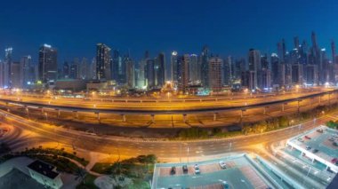 Dubai Marina Gökdelenleri ve Şeyh Zayed Yolu 'nun panoraaması. Gece gündüz metro demiryolu ile geçiş zamanı. Gündoğumundan önce modern kulelerin yakınındaki bir otoyolda trafik vardı, Birleşik Arap Emirlikleri