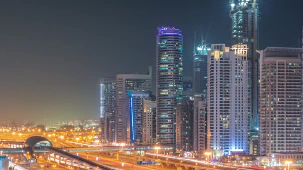 迪拜的滨海摩天大楼和谢赫扎耶德公路 通宵乘坐地铁的飞机 阿拉伯联合酋长国近现代塔楼 窗户闪烁的高速公路上的交通情况 — 图库视频影像