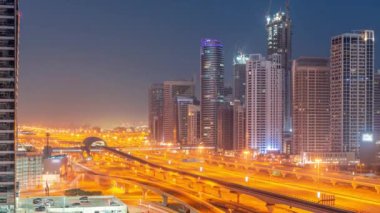 Dubai Marina gökdelenleri ve Şeyh Zayed yolu, gece gündüz metro hava yolu geçiş zamanı. Gündoğumundan önce modern kulelerin yakınındaki bir otoyolda trafik vardı, Birleşik Arap Emirlikleri