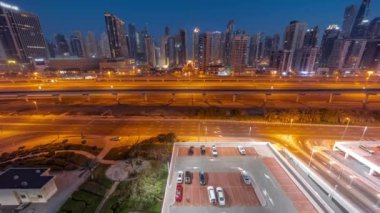 Dubai Marina gökdelenleri ve Şeyh Zayed yolu, gece gündüz metro hava yolu geçiş zamanı. Gündoğumundan önce modern kulelerin yakınındaki bir otoyolda trafik vardı, Birleşik Arap Emirlikleri