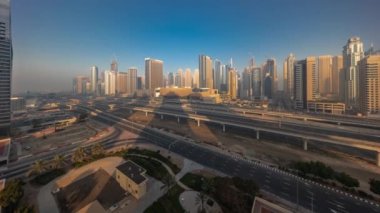 Dubai Marina gökdelenleri ve tüm gün boyunca metro demiryolu panoramik zaman aralıklı Sheikh Zayed yolu. Modern kulelerin yakınındaki otoyolda trafik var. Gölgeler hızla ilerliyor, Birleşik Arap Emirlikleri.