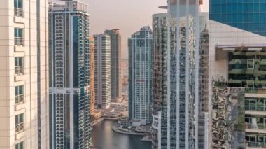 Dubai çoklu emtia merkezi karma kullanım bölgesinin bir parçası olan JLT bölgesi hava zaman diliminde uzun konut binaları. Gün batımında göl kenarındaki gökdelenler